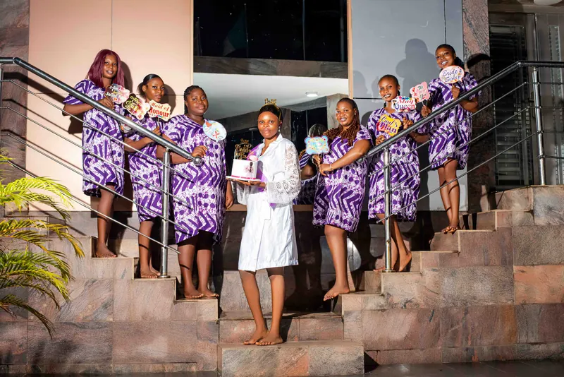 A bride in white with her bridesmaids in matching purple outfits on an outdoor staircase