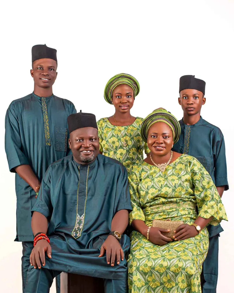 A family of five in matching teal and green traditional outfits